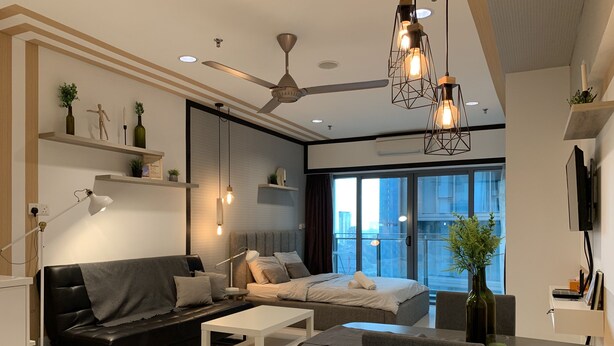 A modern living room with a sofa, a bed, a dining table, and a ceiling fan.