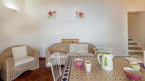 A living room with wicker furniture, a patterned coffee table, and artwork on the wall. - Villa Saluto del Sole (Trinità d'Agultu e Vignola)