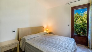 Une chambre à coucher avec un lit, une lampe de chevet et une fenêtre donnant sur un paysage verdoyant.
