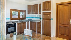 Une cuisine avec des armoires en bois, une cuisinière, un four et une chaise.
