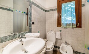 Un baño con un lavabo grande, inodoro, bidé y un espejo.