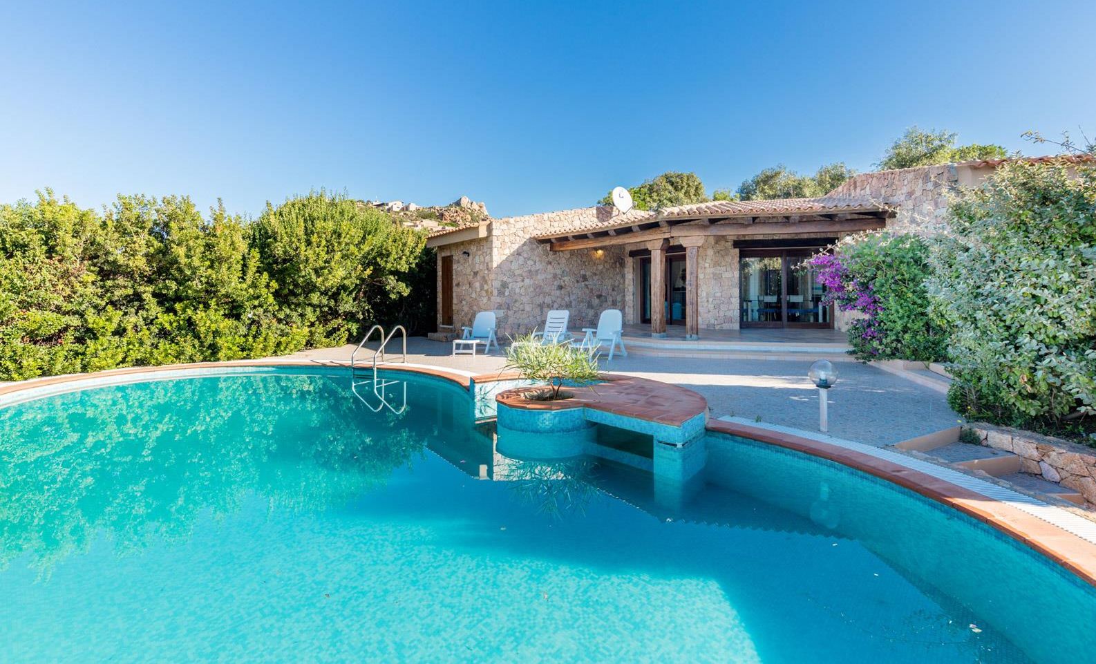 A swimming pool with a stone house in the background.