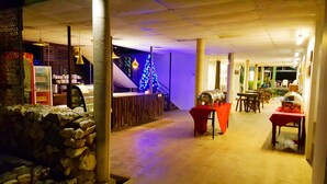 Interior de restaurante con pared de piedra, un árbol de Navidad y mesas al aire libre.