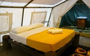 A tented accommodation with a bed, pillows, a small table, and a sink. - Caravan Serai Exclusive Private Villas & Eco Resort (Bentong)