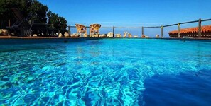 A clear blue pool with lounge chairs and a wooden deck. - Villa Arielle (Trinità d'Agultu e Vignola)
