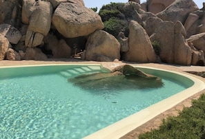 A clear pool with a curved edge, surrounded by large rocks and greenery. - Villetta Ambra Rossa (Trinità d'Agultu e Vignola)