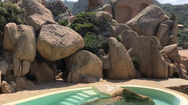 A pool with a clear blue water feature surrounded by large rocks and a stone pathway. - Villetta Ambra Rossa (Trinità d'Agultu e Vignola)
