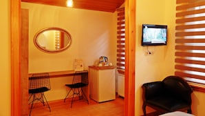 A room with a wooden ceiling, a television mounted on the wall, a small refrigerator, two chairs, and a mirror on the wall. - Belizia Hotel (Istanbul)