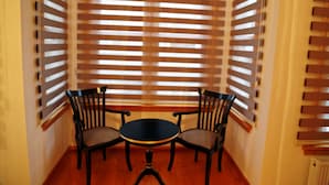 A corner room with a round table and four chairs, wooden blinds on the windows, and a radiator on the wall. - Belizia Hotel (Istanbul)