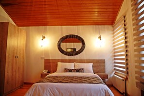 A bedroom with a wooden ceiling, a bed with white bedding, a bedside table with a lamp, and a circular mirror on the wall. - Belizia Hotel (Istanbul)