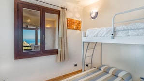 Ein Zimmer mit Etagenbett, einem Vorhangfenster, einer Wandleuchte und Meerblick.
