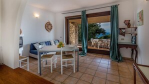 A dining area with a table and chairs, a sofa, and a view of the outdoors. - Villa Porcospino (Trinità d'Agultu e Vignola)