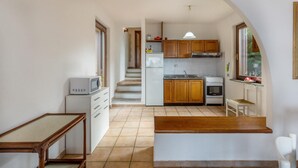 A compact kitchen with wooden cabinets, a built-in oven, and a microwave. - Villa Porcospino (Trinità d'Agultu e Vignola)