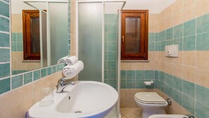 Un bagno con lavandino, WC, bidet e uno specchio.