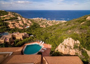 Une villa située sur la côte, dotée d’une piscine, de toits en tuiles de terre cuite et offrant une vue sur la mer.