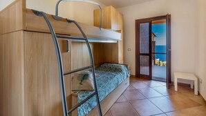 Una stanza con un letto a castello, una scala, una piccola panca e una porta che dà su un balcone con vista.