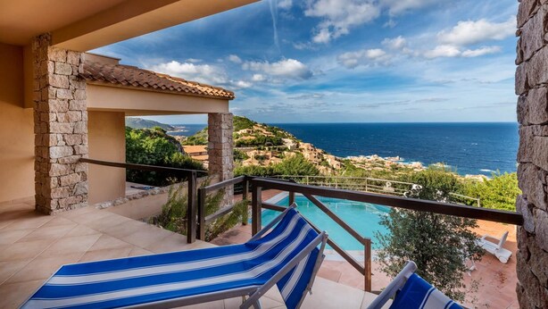 Un balcone con piscina, colonne in pietra e vista sul mare e sulle colline.