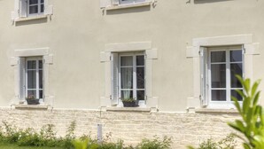 Um edifício com várias janelas, degraus de pedra e vasos de plantas nos parapeitos.