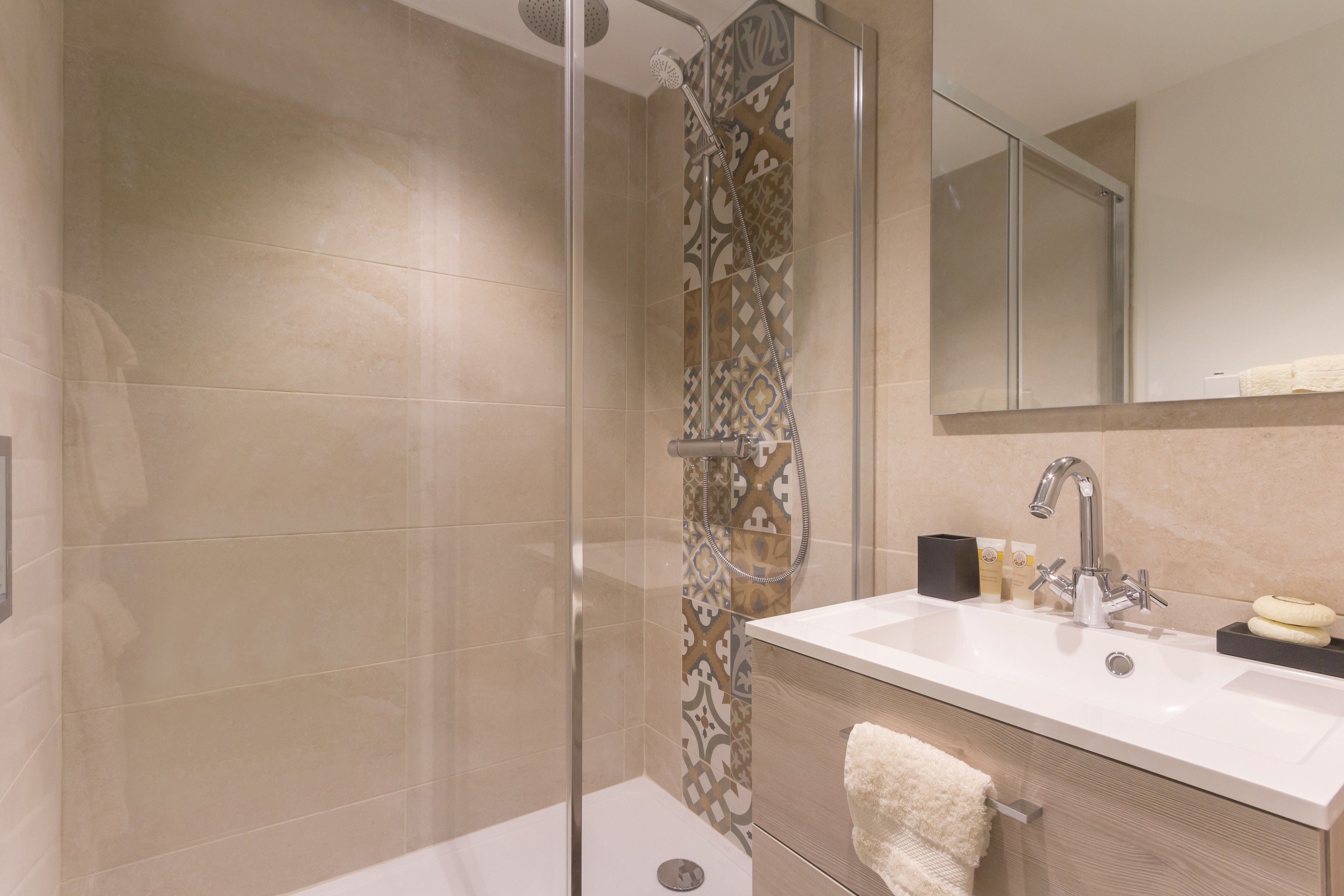 A modern bathroom with a glass-enclosed shower, a white sink, and a large mirror.
