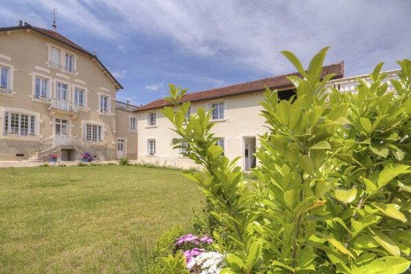 A two-story building with a stone facade, multiple windows, and a red-tiled roof. - L'Escale de Jules et Lily (Bligny-lès-Beaune)