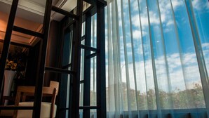 A room with a large window, a chair, and a table with a vase of flowers. - HE&LE Design Hotel (Taichung)