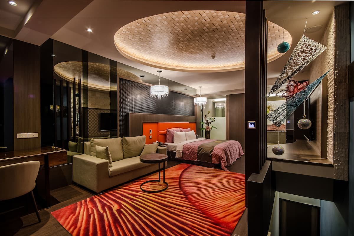 Una habitación de hotel moderna con techo curvo, un sofá, una cama y una mesita.