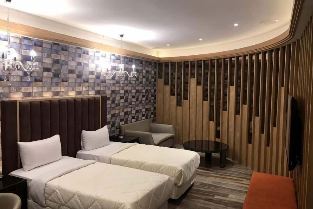 Una habitación de hotel con dos camas, un sofá, un televisor y una mesita.