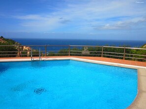 A swimming pool with a view of the ocean, surrounded by a fence and a sign that reads "Paradise Residence".