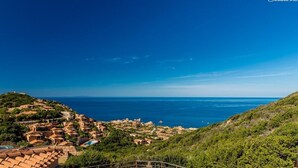 A coastal village with terracotta-roofed buildings, a clear blue sky, and the sea in the background. - Casa Rosa Quattro (Trinità d'Agultu e Vignola)