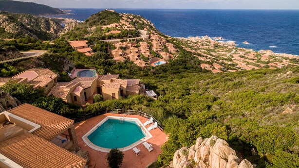 A coastal resort with terracotta-roofed buildings, a swimming pool, and a view of the sea. - Casa Rosa Due (Trinità d'Agultu e Vignola)