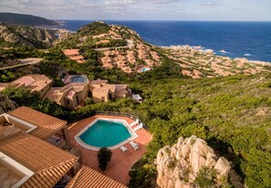 A coastal resort with terracotta-roofed buildings, a swimming pool, and a view of the sea. - Casa Rosa Due (Trinità d'Agultu e Vignola)