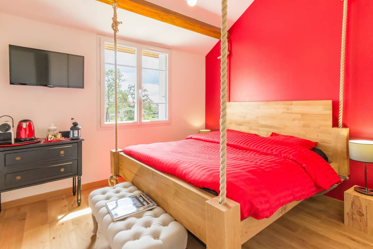 Une chambre à coucher avec un lit, un bureau, une chaise, une télévision et une fenêtre.