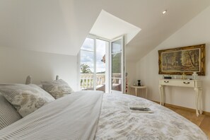 Ein Schlafzimmer mit einem großen Bett, einem Oberlicht, einem Balkon und einem Gemälde an der Wand.