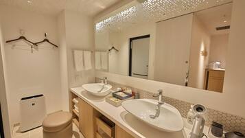 A modern bathroom with two sinks, a toilet, and a large mirror.
