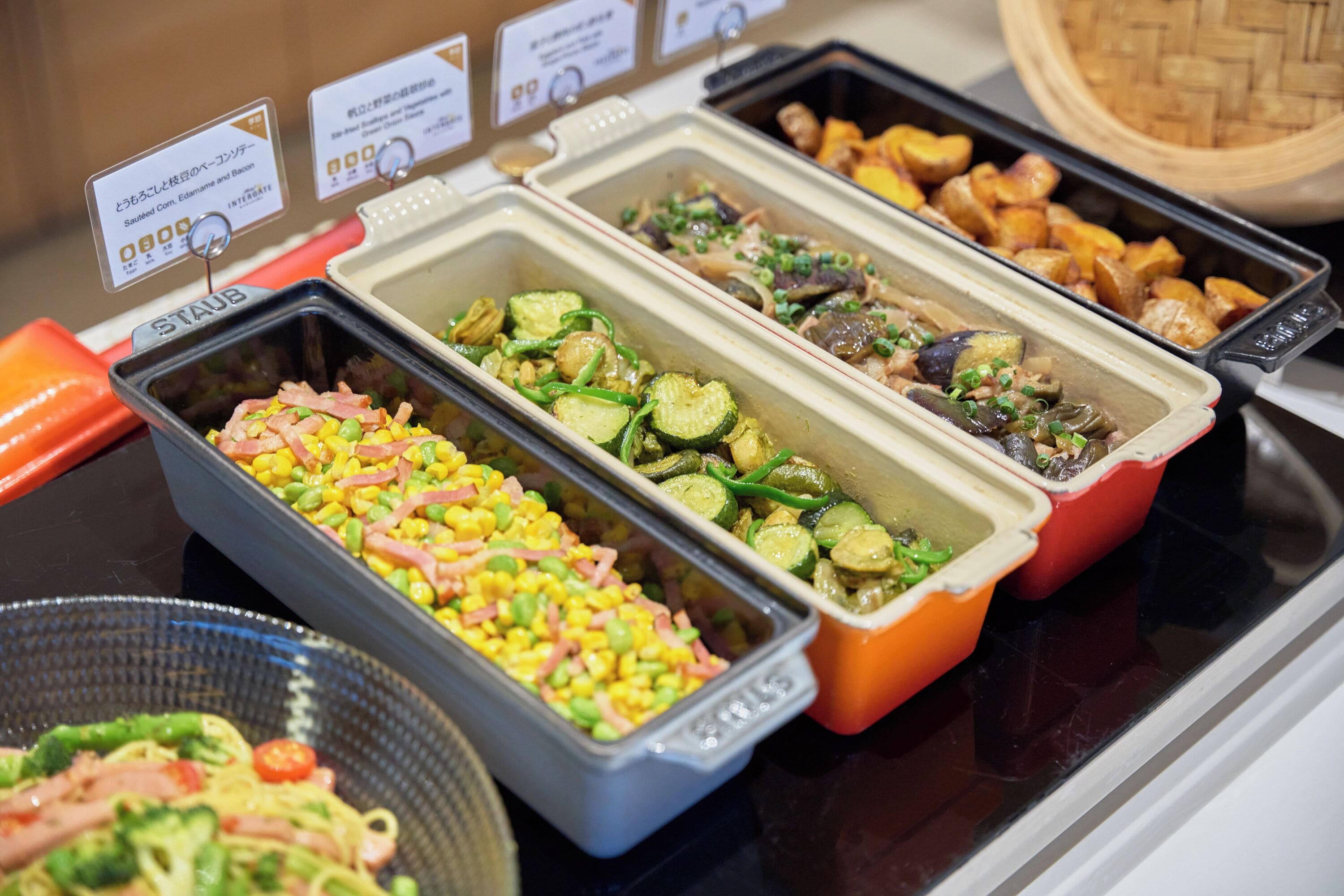 A buffet with various dishes including vegetables, meats, and salads.