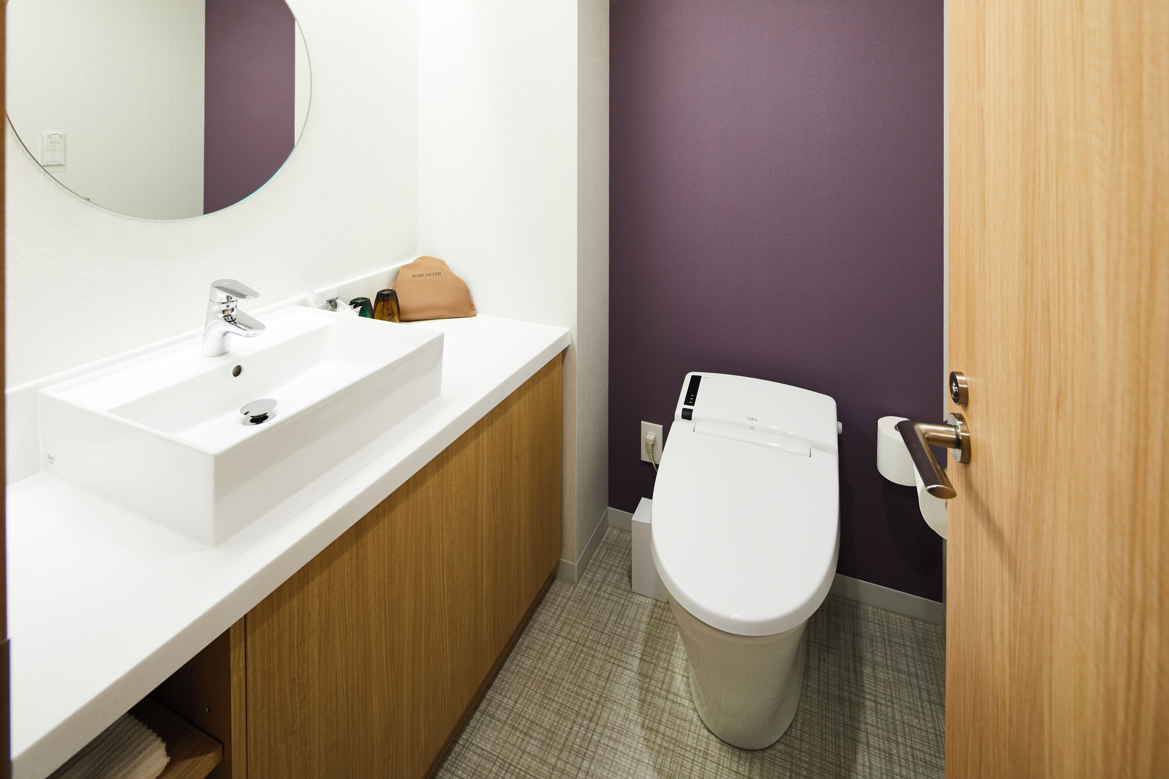 Un baño con lavamanos blanco, espejo, inodoro y puerta de madera.