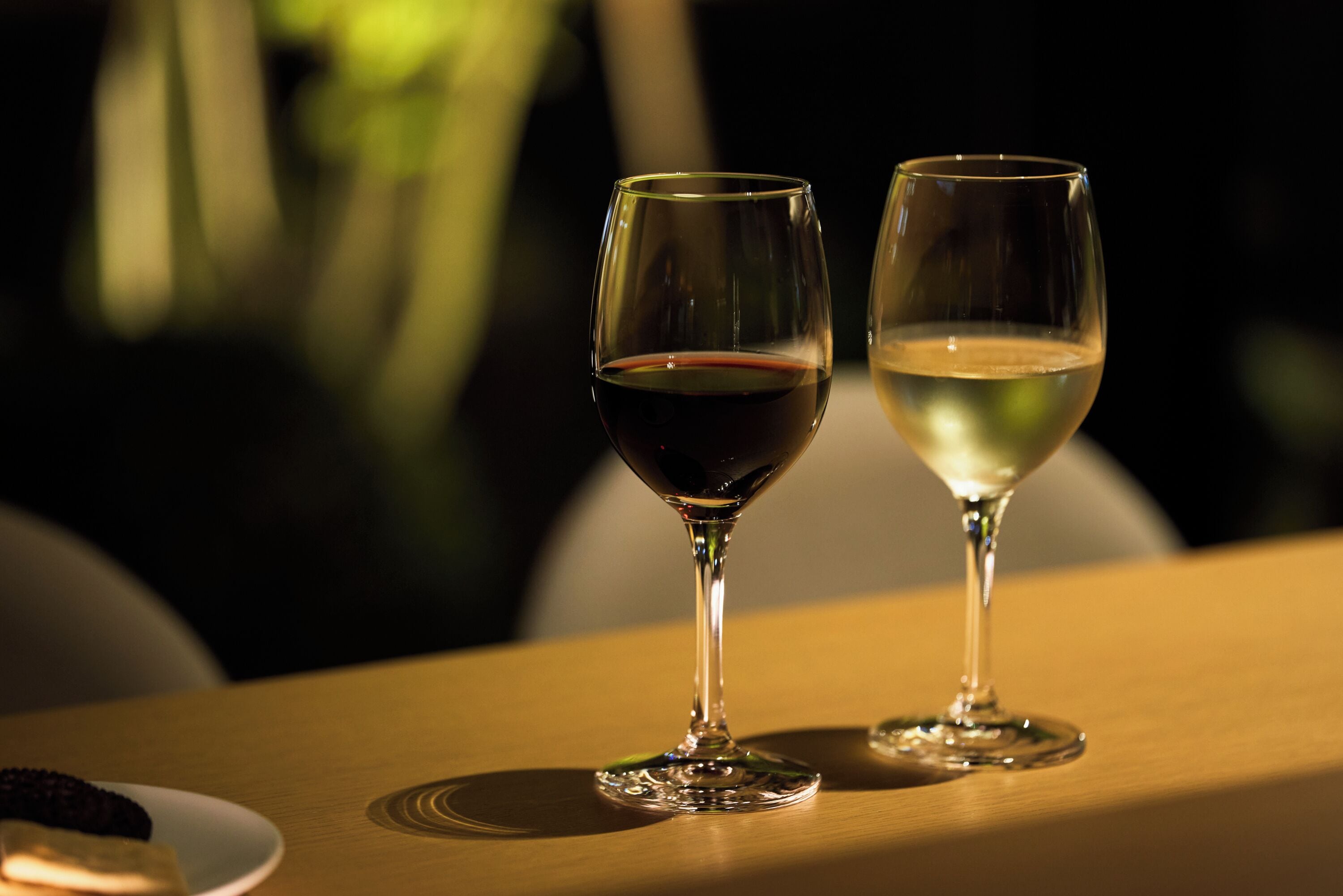 Two wine glasses on a wooden table with a blurred background.