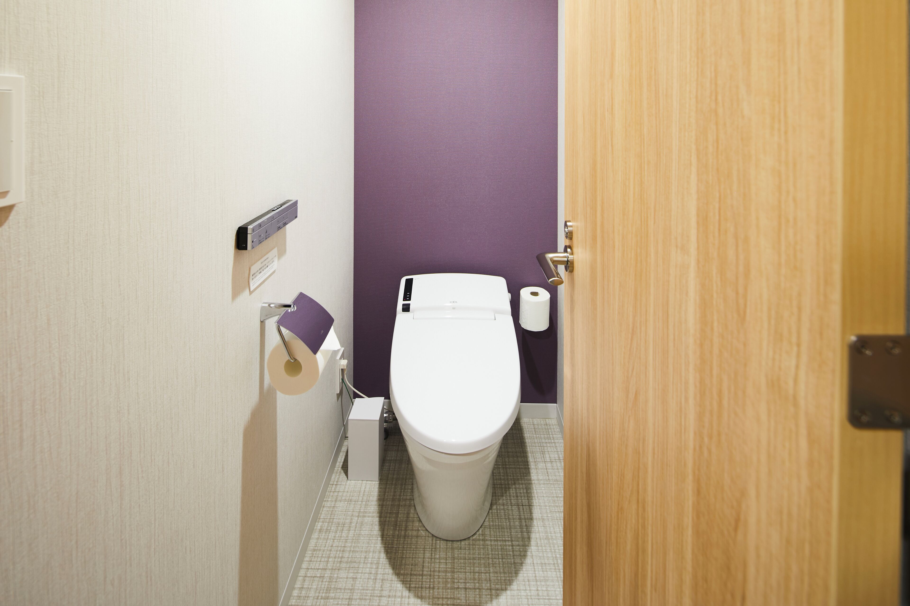 Un baño pequeño con un inodoro, un dispensador de toallas de papel y un rollo de papel higiénico.