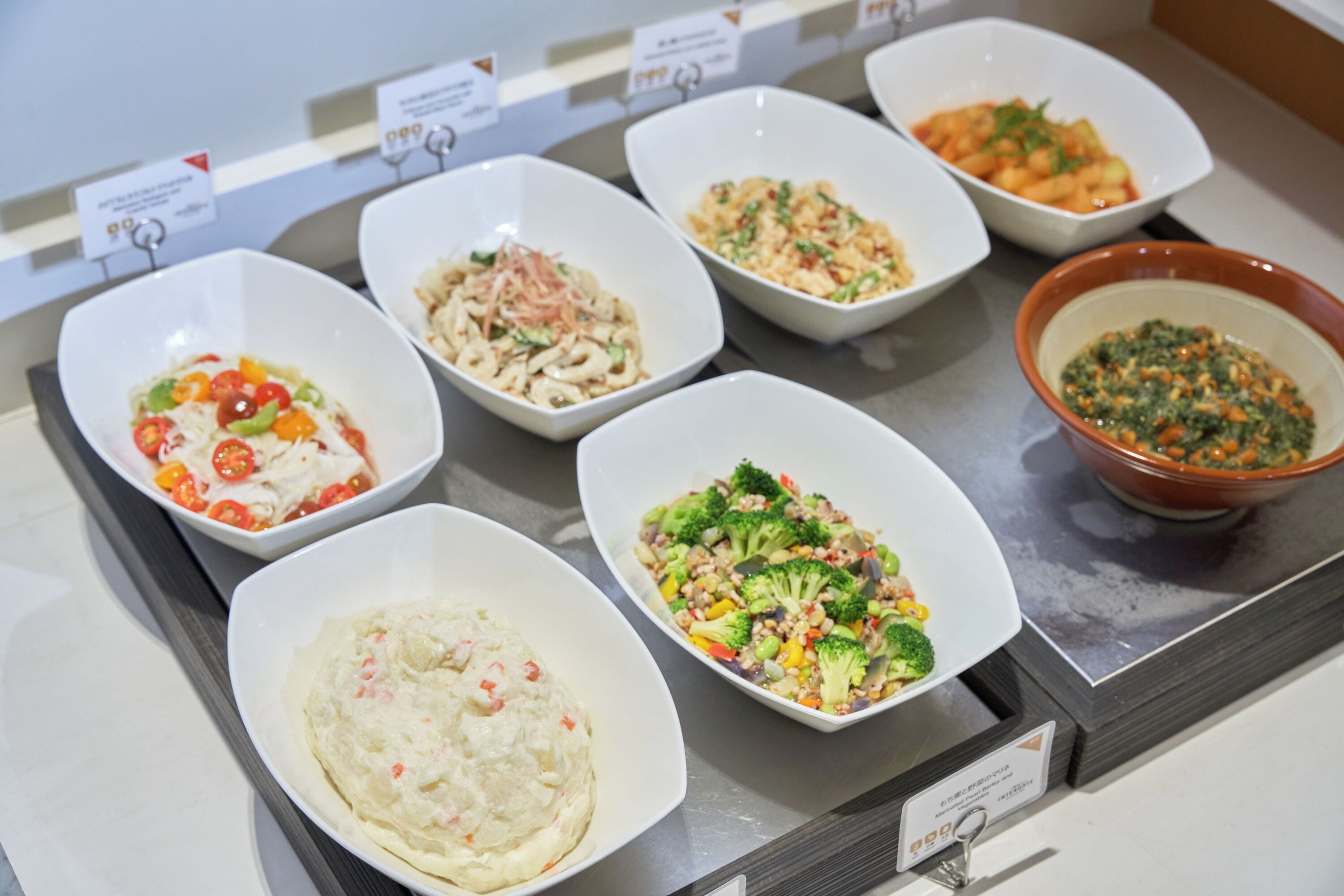 Buffet com diversos pratos em tigelas, incluindo massa, saladas e uma sopa.