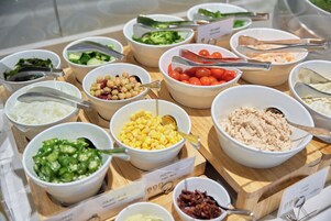 Un bufé con diversos platos, incluyendo ensaladas, verduras y otras opciones de comida.