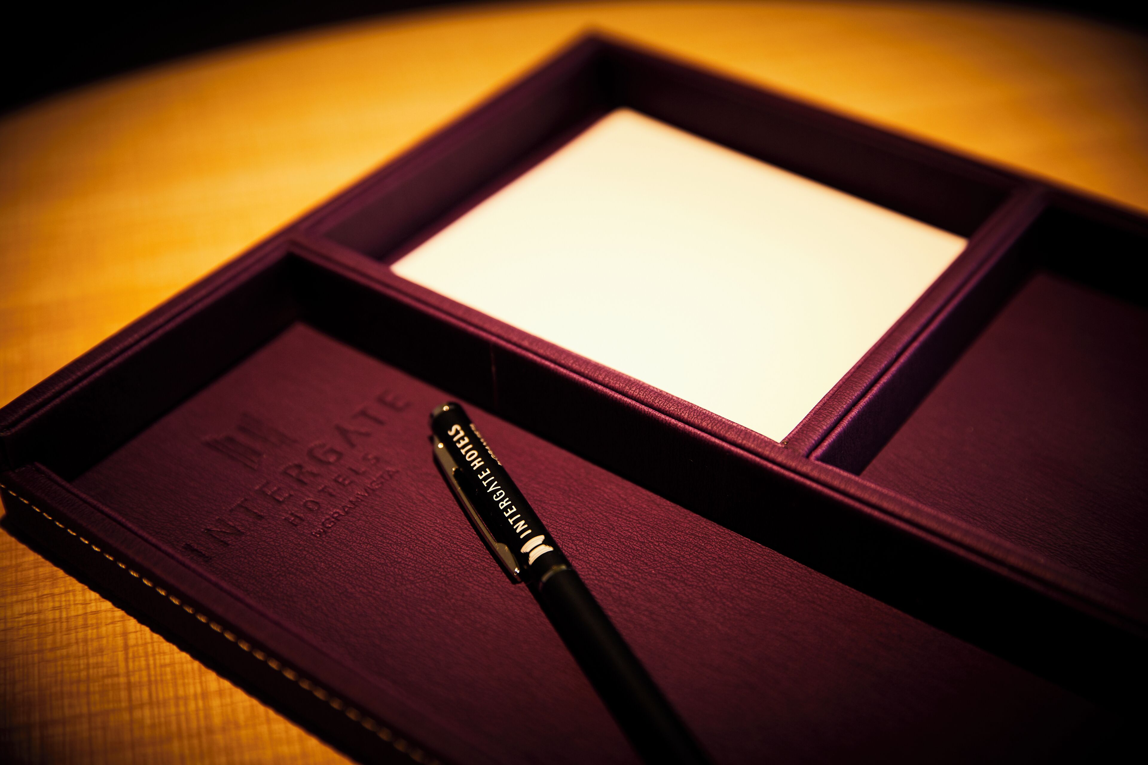Un carnet à couverture en cuir violet sur lequel est inscrit le texte « INTERROGAT HOTEL ».