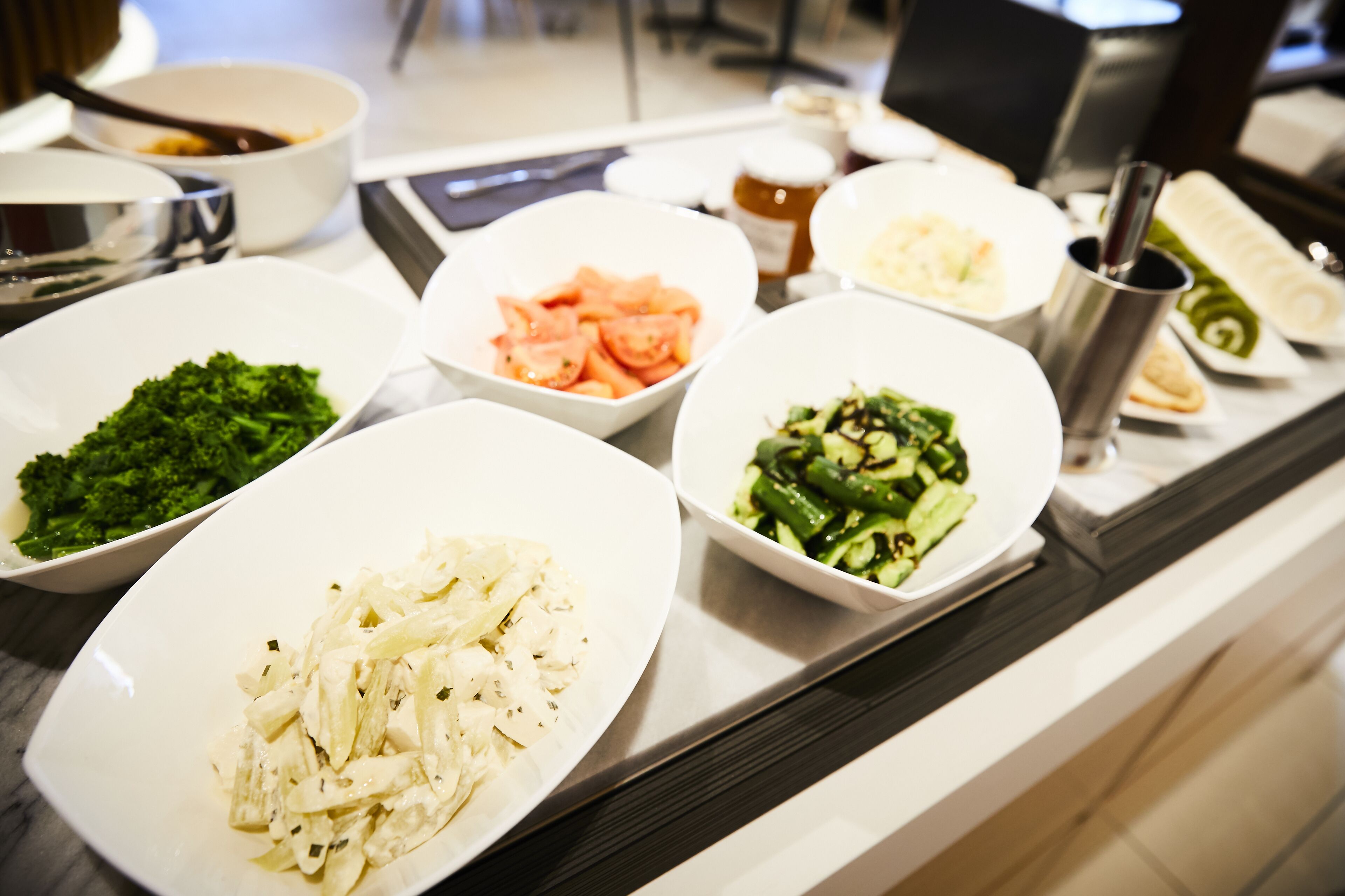 A buffet table with various dishes including broccoli, carrots, and a salad.