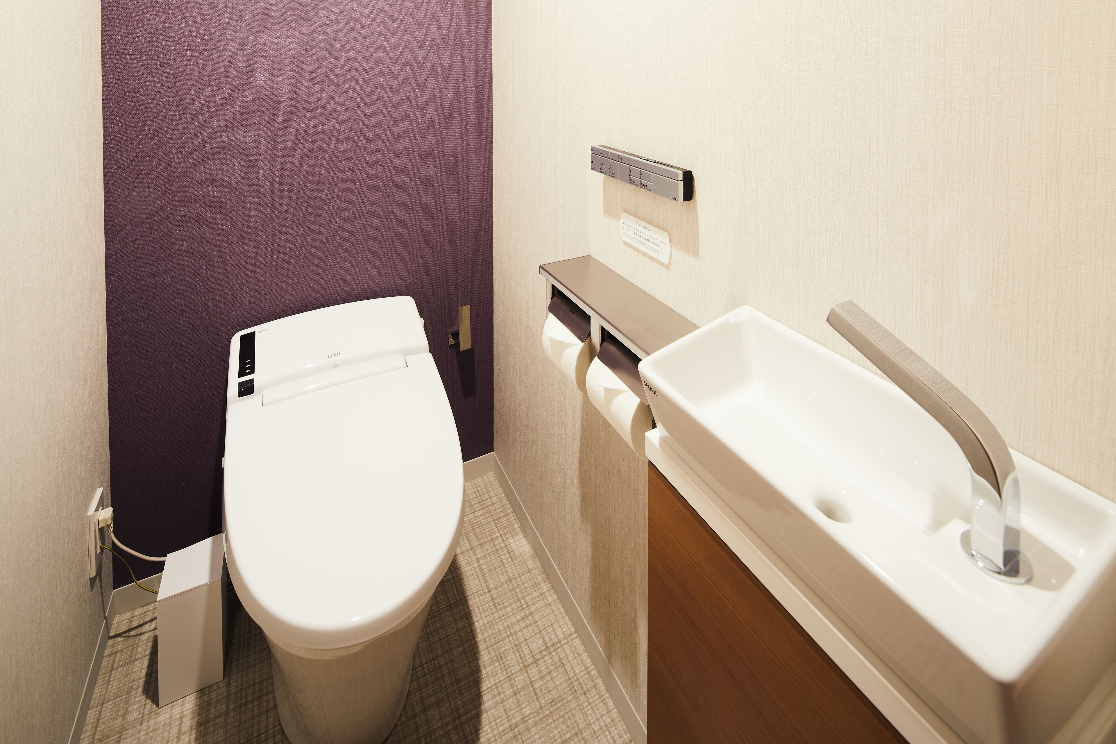 Une petite salle de bain comprenant des toilettes, un lavabo et un distributeur de serviettes.