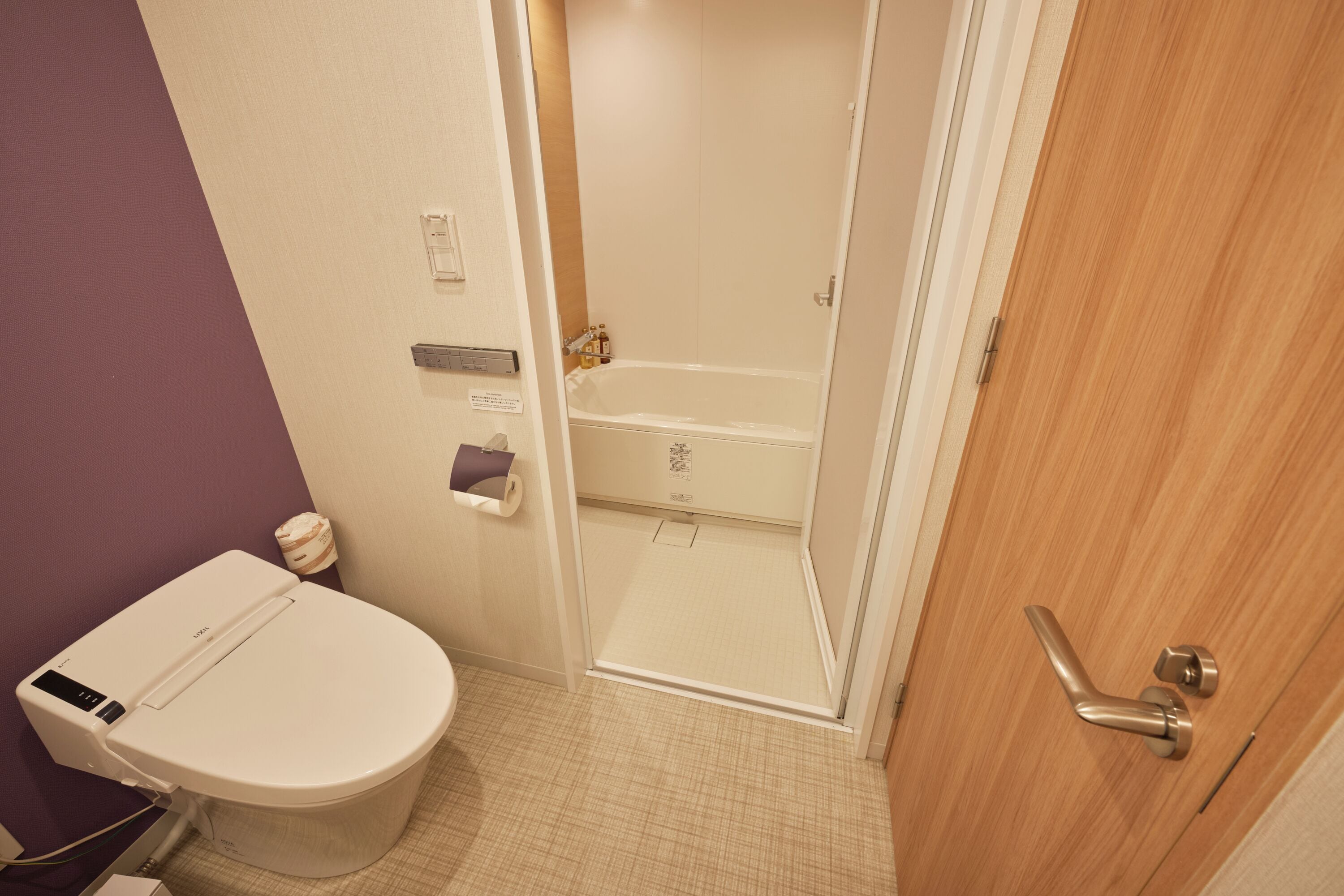 A bathroom with a toilet, a shower, and a wooden door.