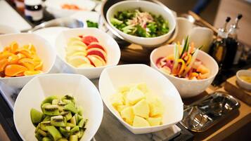 Une table de buffet proposant une variété de fruits et de salades.