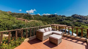 A terrace with wicker furniture and a view of a mountainous landscape. - Villa Violetta 3 Verde (Trinità d'Agultu e Vignola)