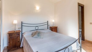 A neatly arranged bedroom with a single bed, two bedside tables with lamps, and a wooden cabinet. - Villa Violetta 5 Rossa (Trinità d'Agultu e Vignola)