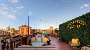 A rooftop terrace with a sofa, chairs, and a decorative wall with a sign. - Hotel Chapter Roma (Rome)
