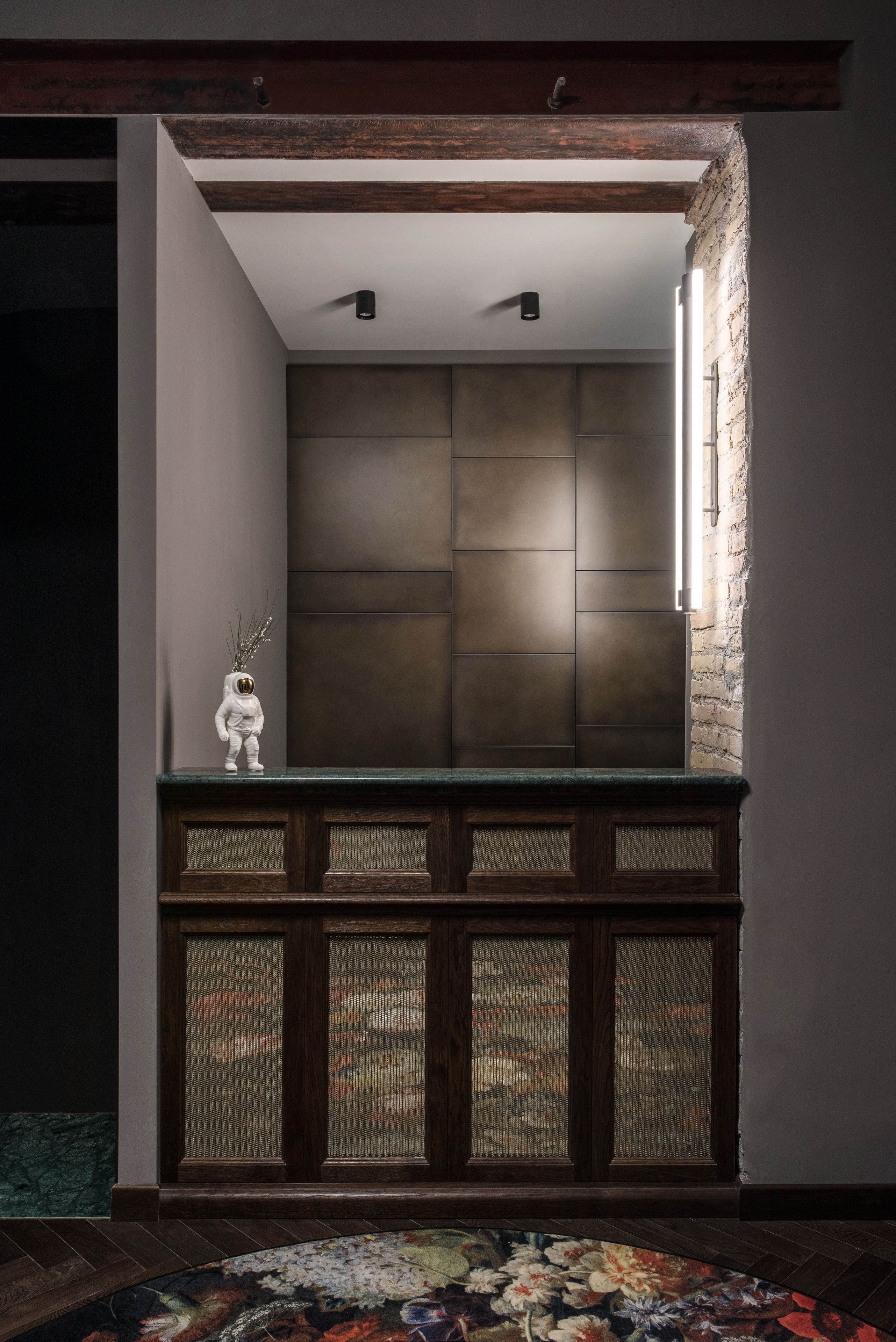 Un interior moderno con un banco de madera, un jarrón decorativo y una alfombra estampada.