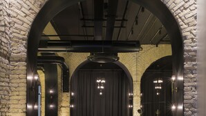 A modern interior with a brick wall, a curved archway, a sofa, and a bar area. - Hotel Chapter Roma (Rome)